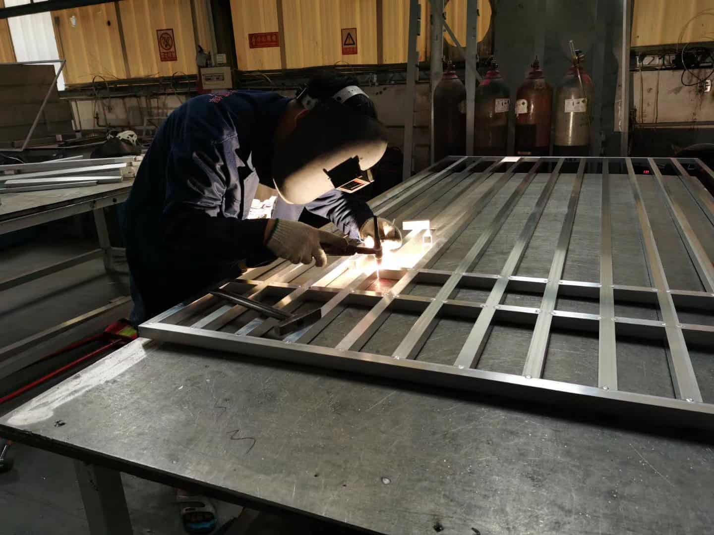 Close-up of a welder working on aluminum extrusions with sparks flying
